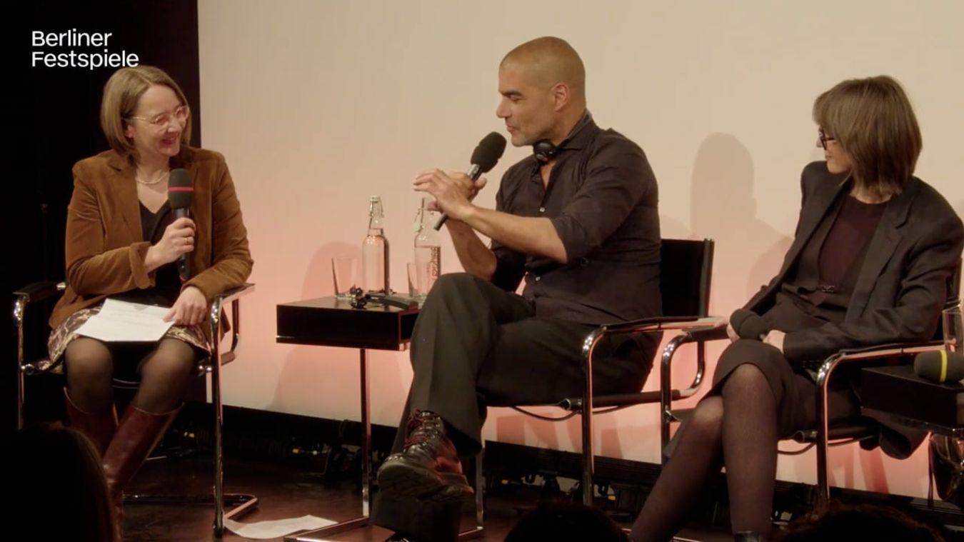 Personen sitzen auf einer Bühne und schauen zueinander.