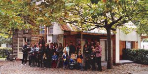 A group photo in front of a wooden hut in a car park