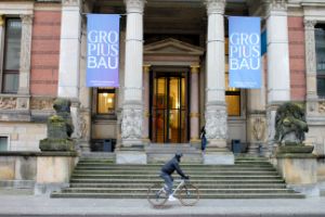 A person rides past the Gropius Bau on a bicycle.