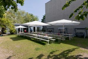 In the garden of the Haus der Berliner Festspiele there are long white tables with white beer benches and white parasols.