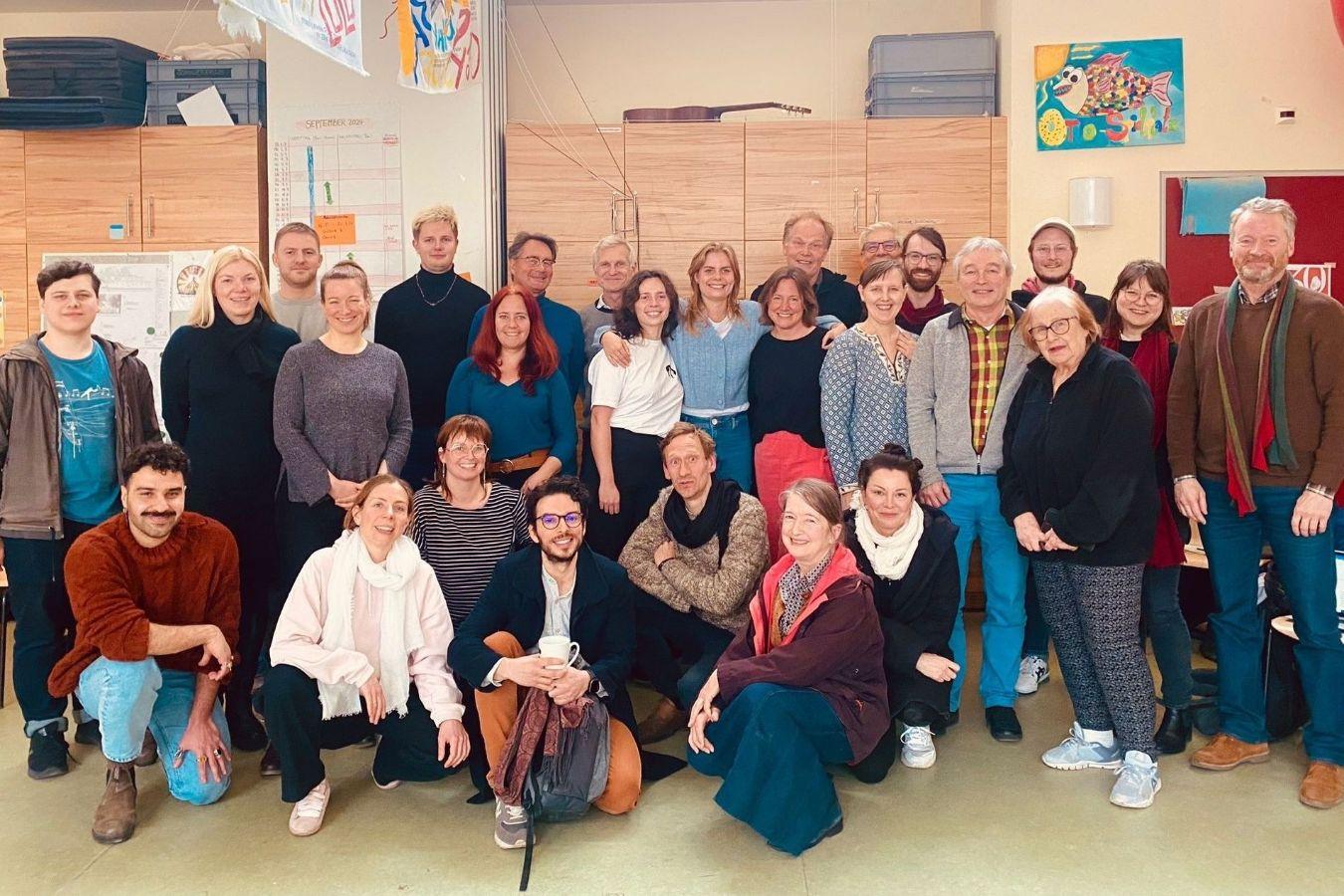 Guppenbild mit zwei Dutzend Personen in einem Klassenzimmer.