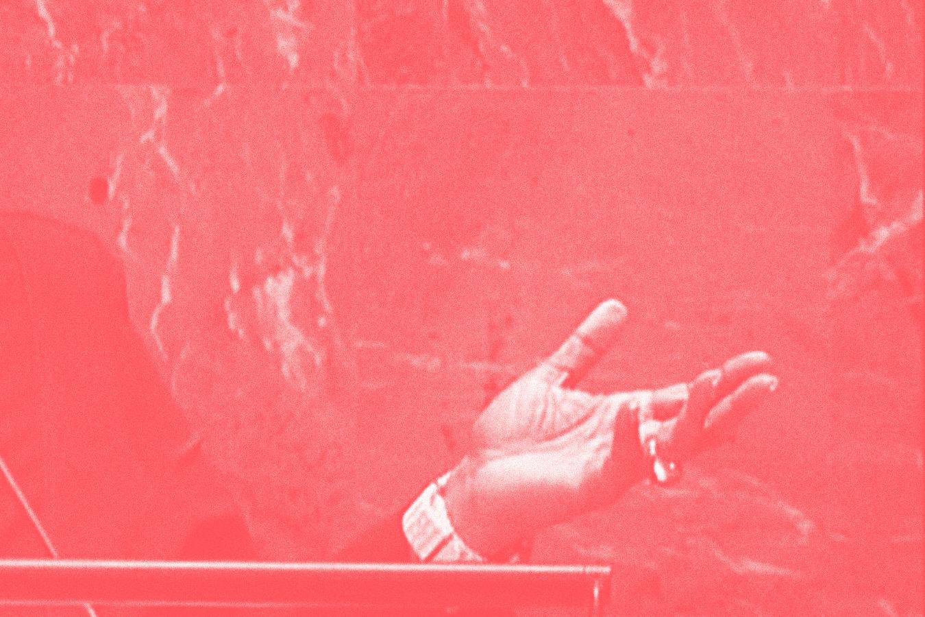 A left hand in an inviting gesture. The photo is reddish in colour and appears archival.