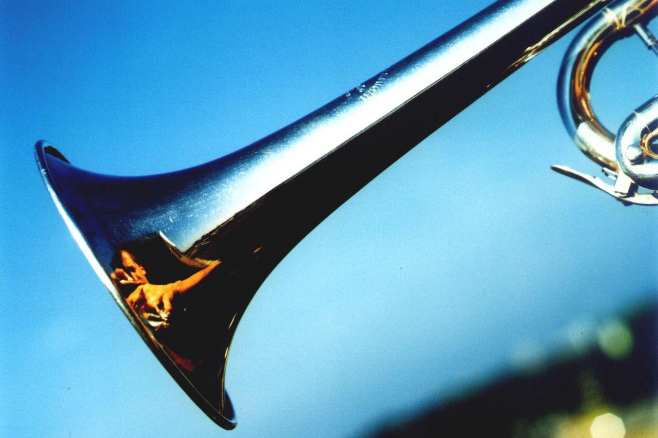 The bell of a trumpet, in whose glow Marco Blaauw is reflected