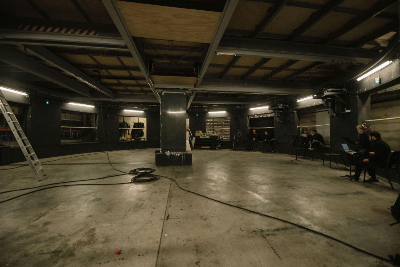 Lower stage in the Haus der Berliner Festspiele. A ladder stands at the left edge of the picture, a cable lies on the floor, musicians sit on the right.