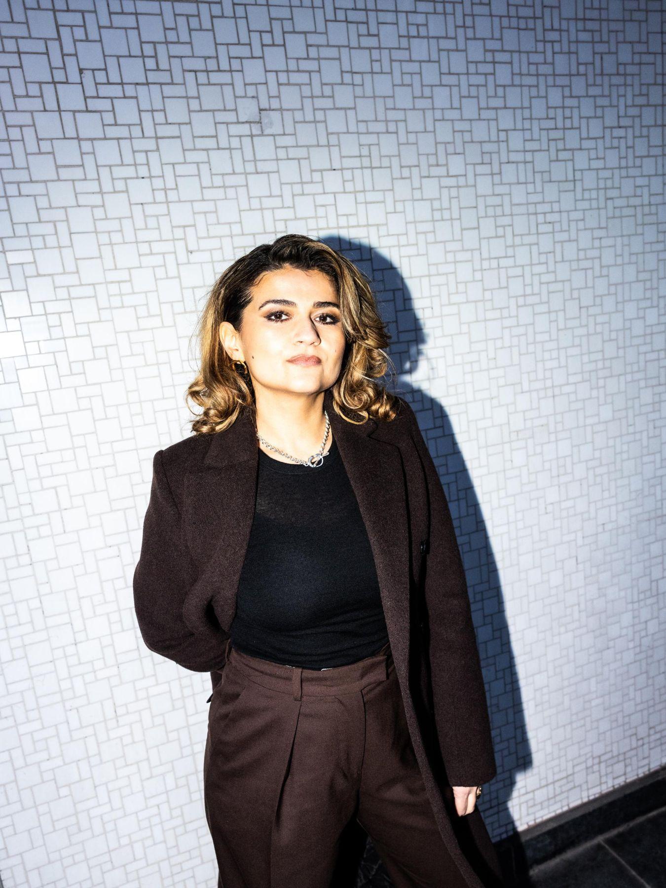 Pınar Karabulut is standing in front of a wall