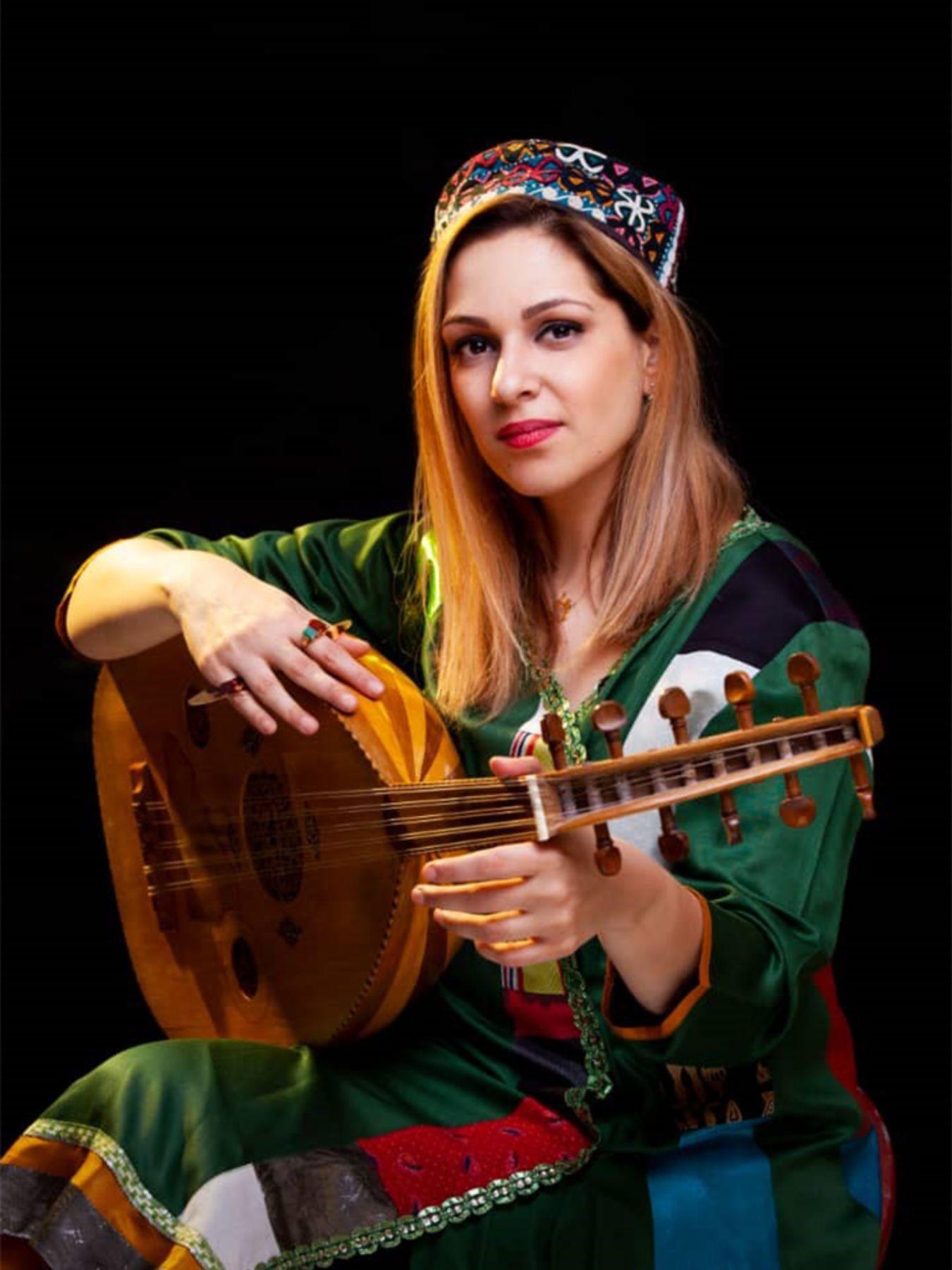 A woman in traditional dress with an oud on her lap.