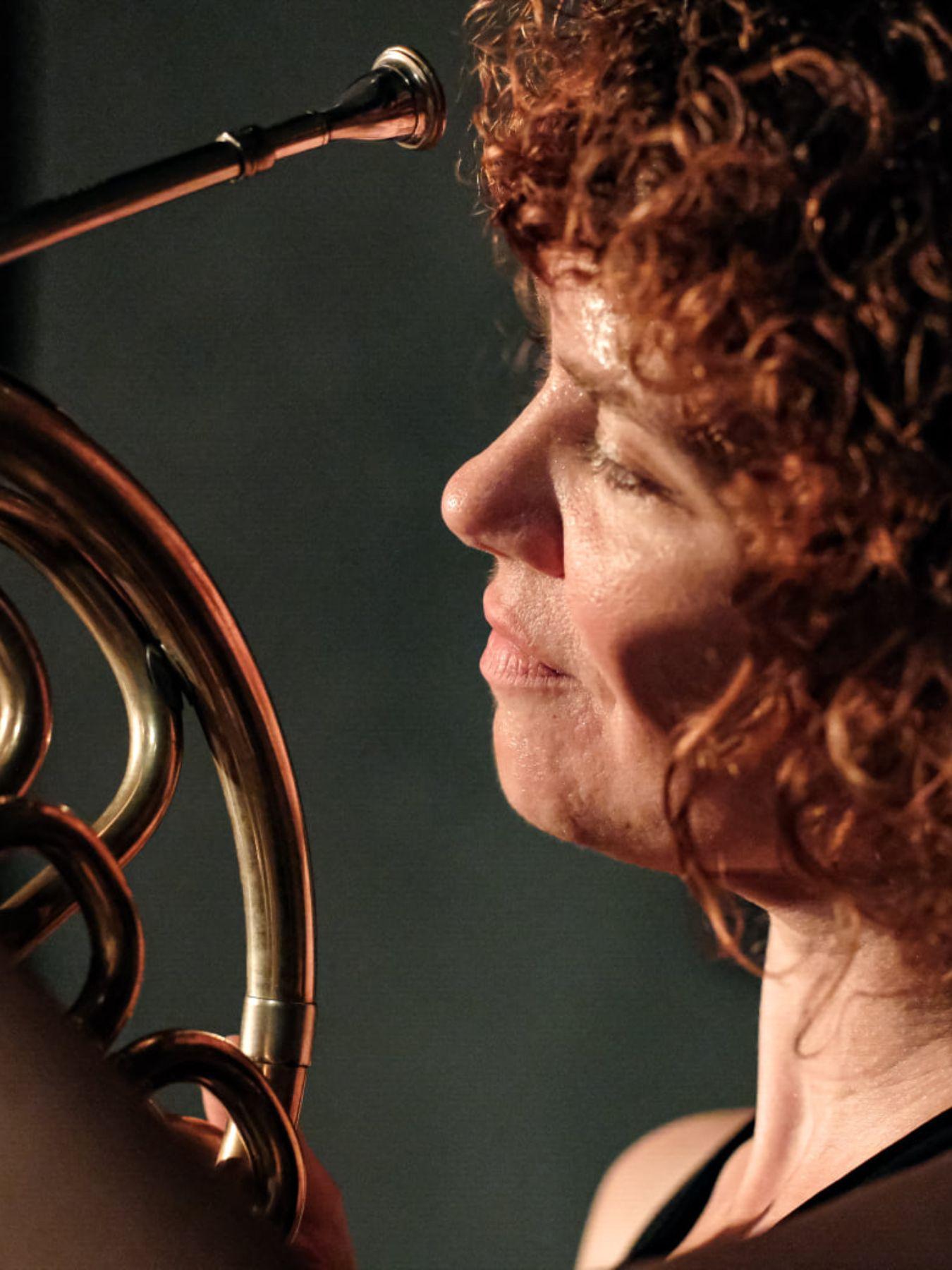 Kakaliagou has red curls and looks at her horn.