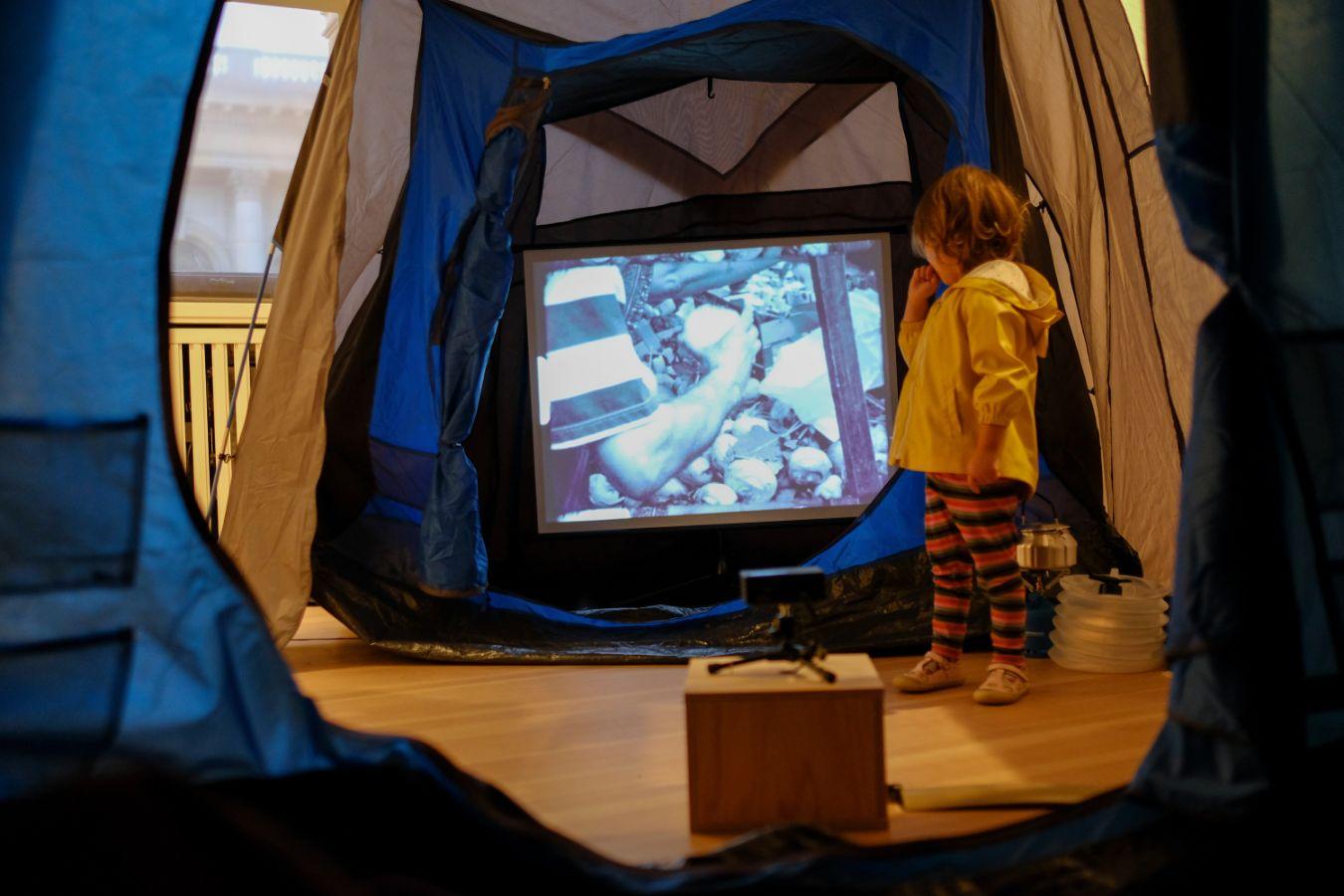 Installation view of Rirkrit Tiravanija's "untitled 1997 (cinéma de ville, berlin - bangkok)" with a child as part of the exhibition "Rirkrit Tiravanija: DAS GLÜCK IST NICHT IMMER LUSTIG" at Gropius Bau, 2024.