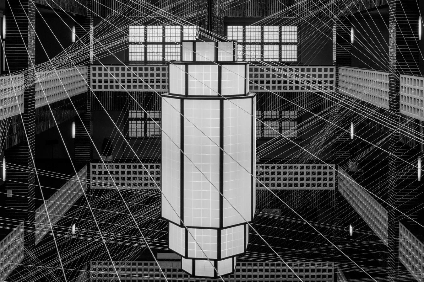 A net of wires is stretched across the foyer of the Haus des Rundfunk in front of a large lamp.