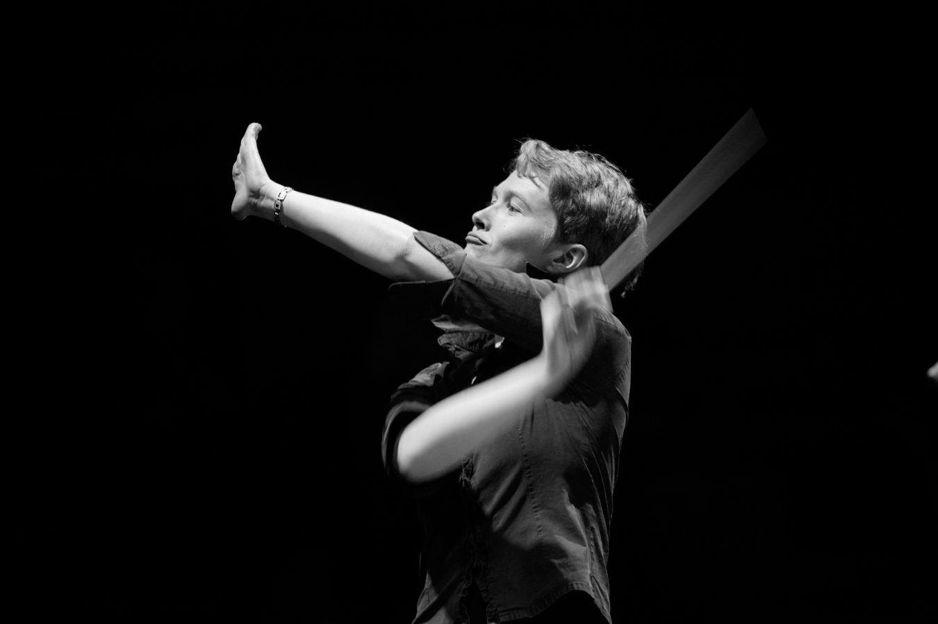 A woman conducts with raised arms.