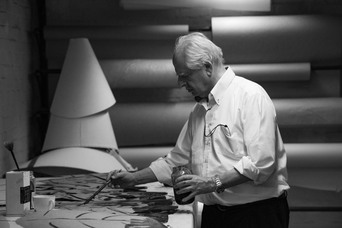 Kentridge looks focused while painting palm leaves cut out of cardboard.