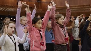 A group of children raise their arms in the air.