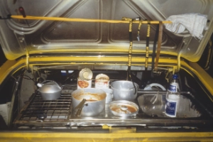 An open boot of a yellow car containing various cooking utensils.