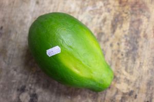 Eine leuchtend grüne Papaya, auf der ein Preisschild mit dem Aufdruck ”€13.00“ klebt.