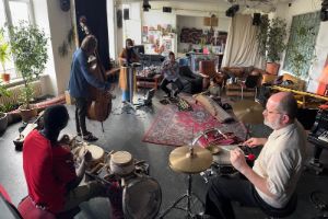 Musiker*innen spielen in einem Proberaum