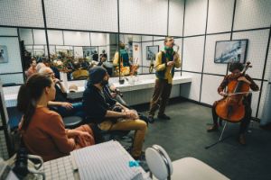 An ensemble plays in a tiled room with many mirrors