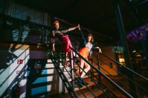 Two people stand on a staircase and clasp their hands over their heads.