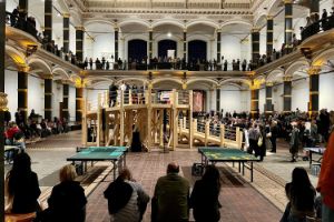 Viele Menschen stehen und sitzen im Lichthof des Gropius Bau bei einer Veranstaltung.