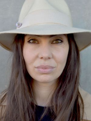 Portrait of a person with a hat in front of a grey wall