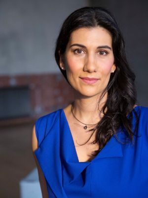 A female person with long dark hair looks directly into the camera