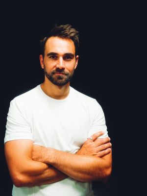 A portrait of a person in a white T-shirt against a black background