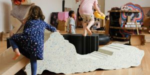 Children play in a room with colourful structures.