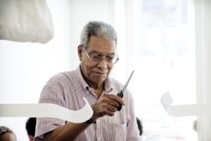 Der Fluxuskünstler Benjamin Patterson zerschneidet mit der Schere Papierstreifen.