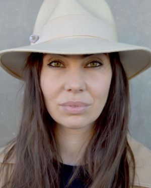 Portrait of a person with a hat in front of a grey wall