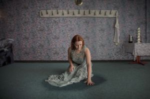 Eine Frau kniet in einem grauen Abendkleid auf dem Boden.