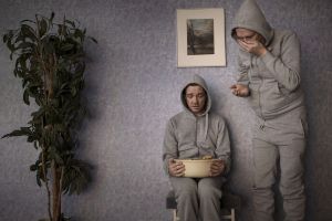 Two men in grey tracksuits look in horror into a bowl.