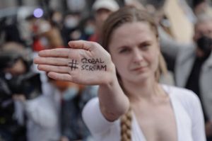 A young woman holds her palm up to the camera, which reads: “#Global Scream”.