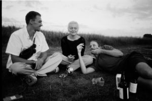 Two men and a woman sit relaxed on a lawn. The picture is in black and white.