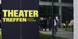 A dark blue poster with the yellow lettering “Theatertreffen” in front of the Haus der Berliner Festspiele