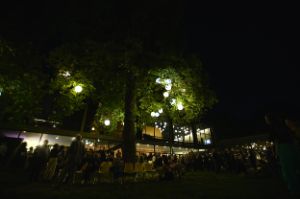 Audience gathers at night in front of the Haus der Berliner Festspiele at the Theatertreffen 2024.