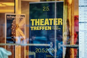 A blue Theatertreffen poster hangs between colourful Schaubühne posters.