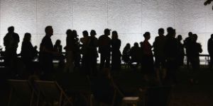 A group of people stand in the garden of the Haus der Berliner Festspiele at night.
