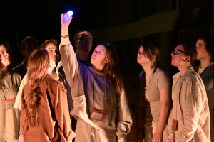 Eine Gruppe junger Menschen schauen auf ein leuchtendes Objekt.