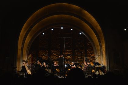The International Contemporary Ensemble performs on a stage framed by a large arch.